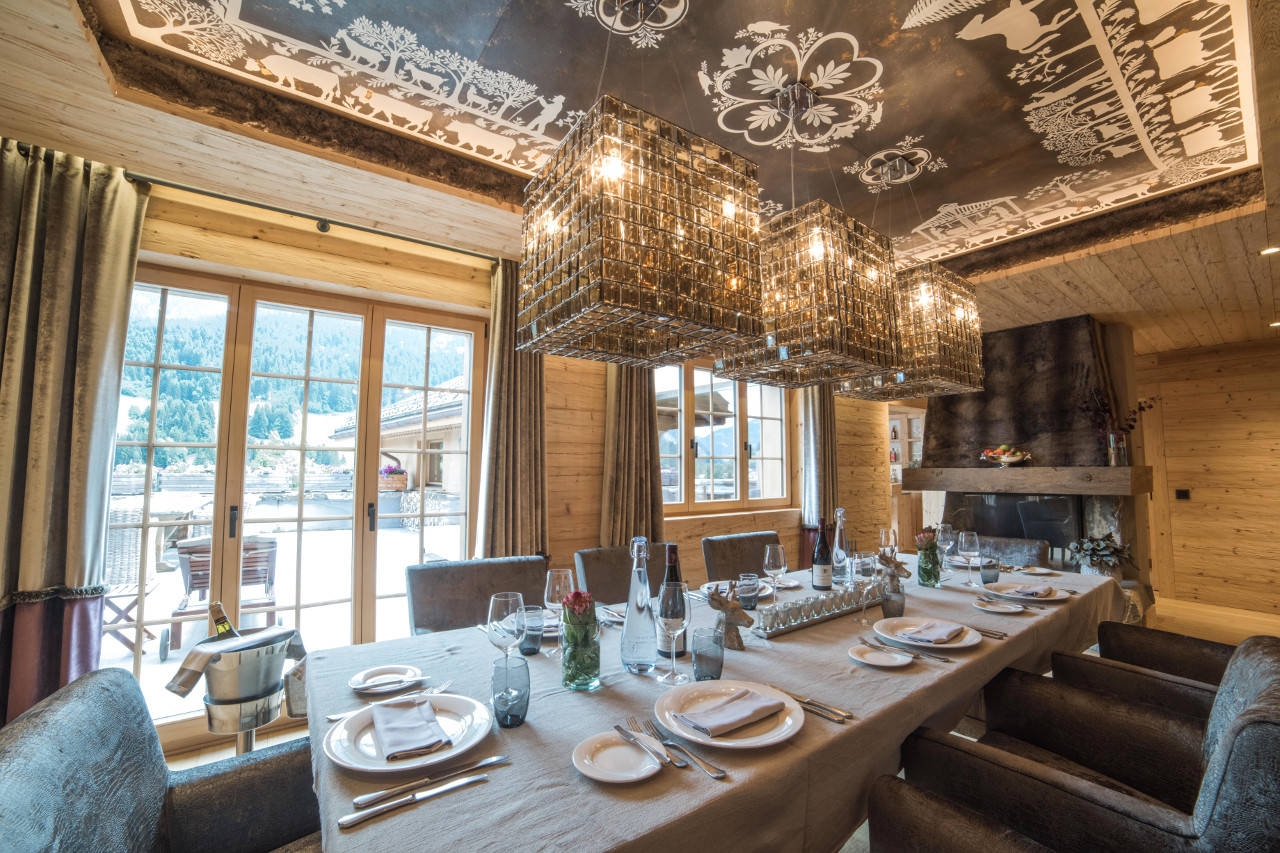 Dining room with painted ceiling and access to terrace in Chalet de Rougemont in Gstaad