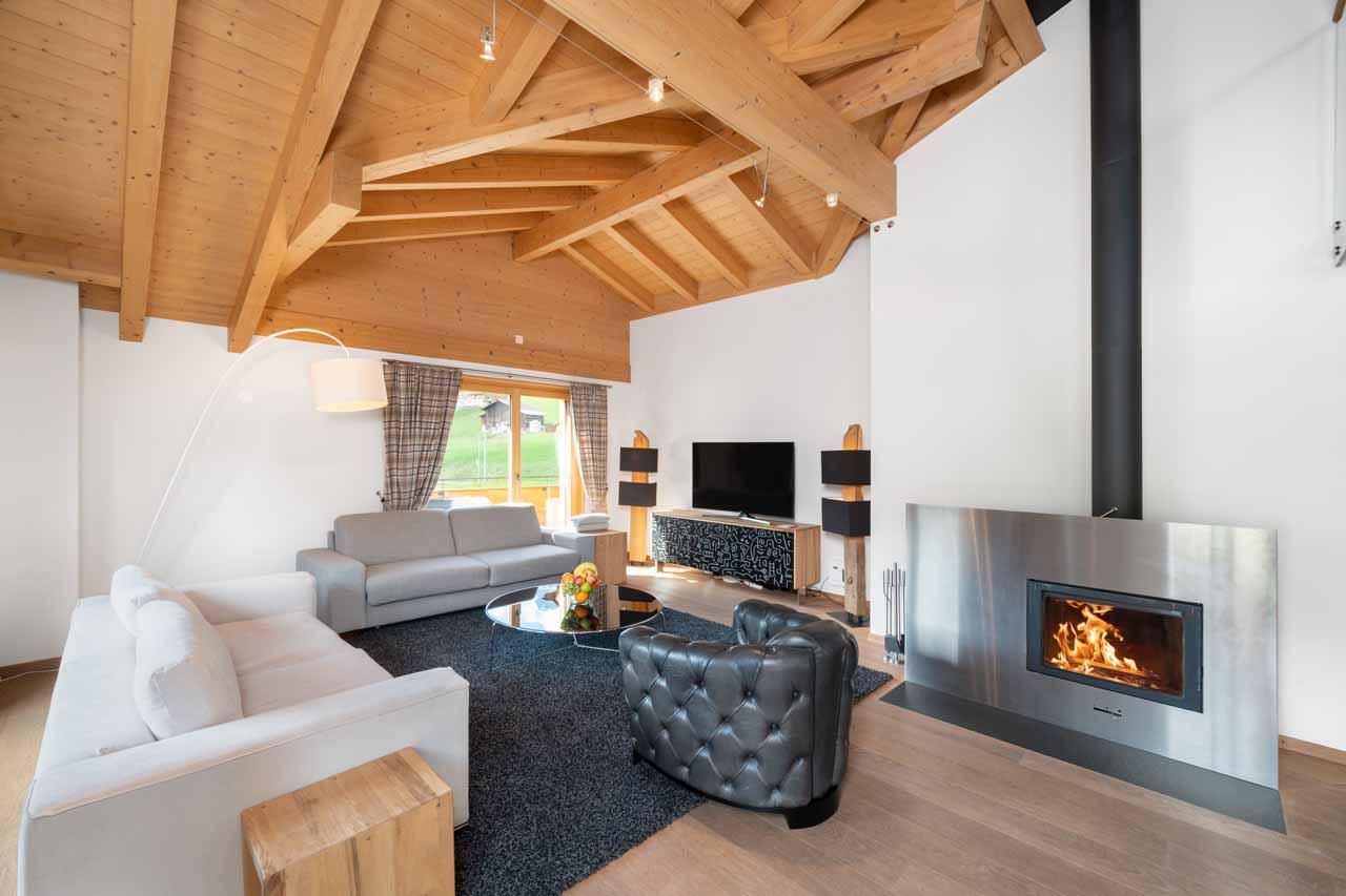 Open-plan living space with fireplace at Apartment Antara in Grindelwald