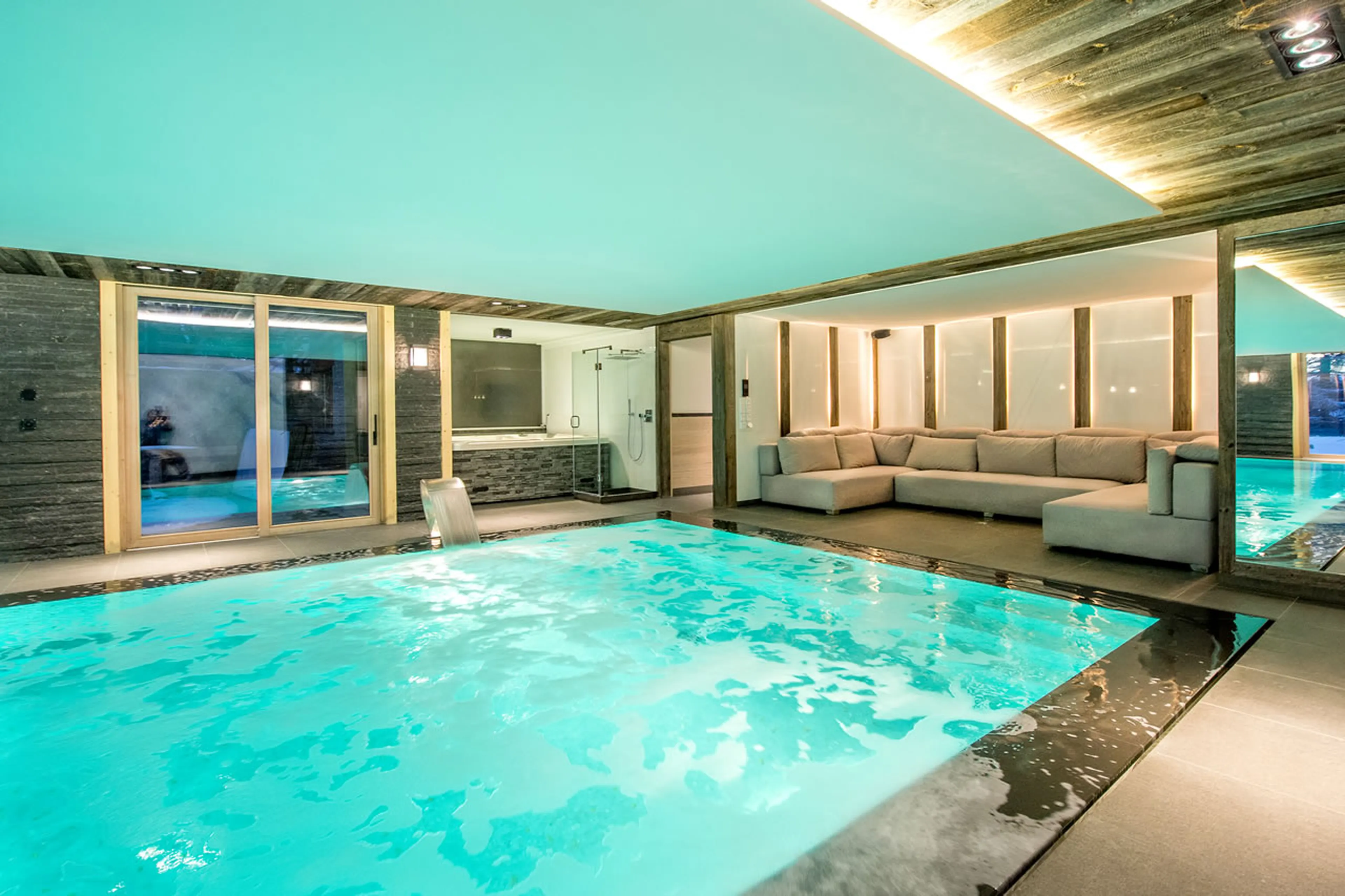 Indoor swimming pool with relaxation area and shower in Apartment Aminona in Crans-Montana