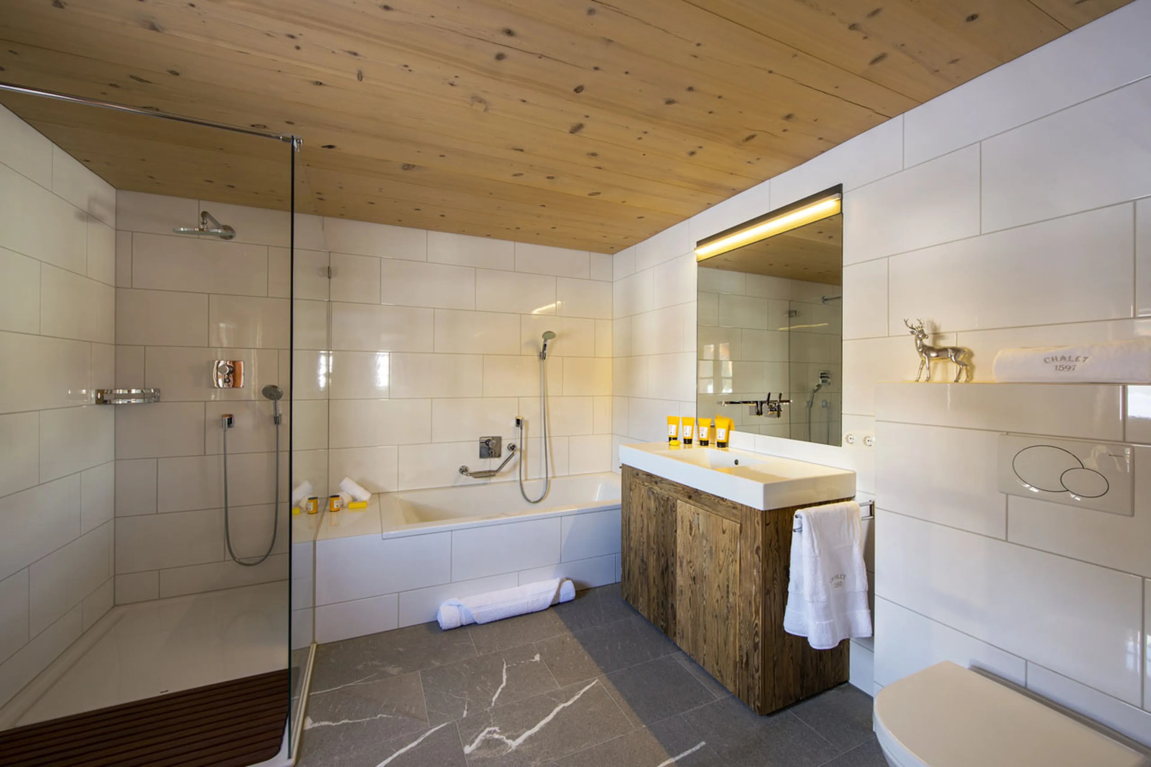 Modern en suite bathroom with bath and shower in Chalet 1597 in Lech