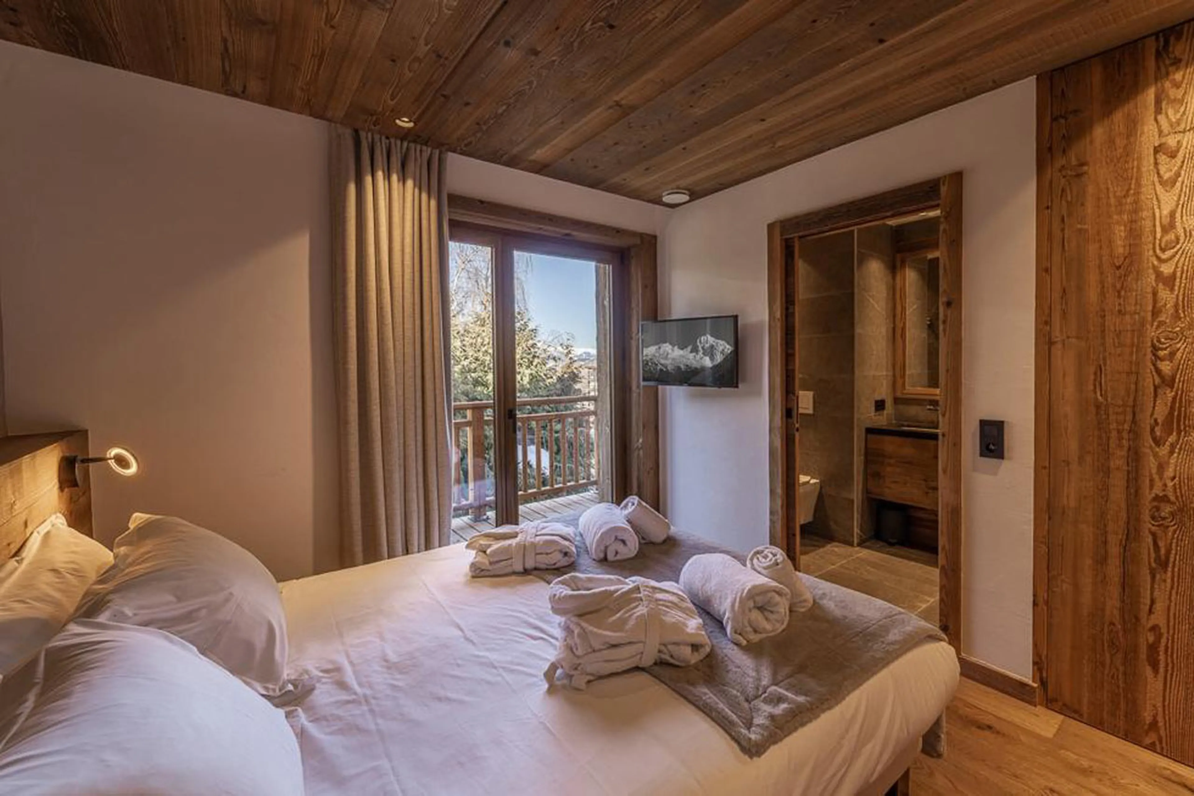 Bedroom one with balcony access at Chalet Bois des Barmes in Courchevel La Praz