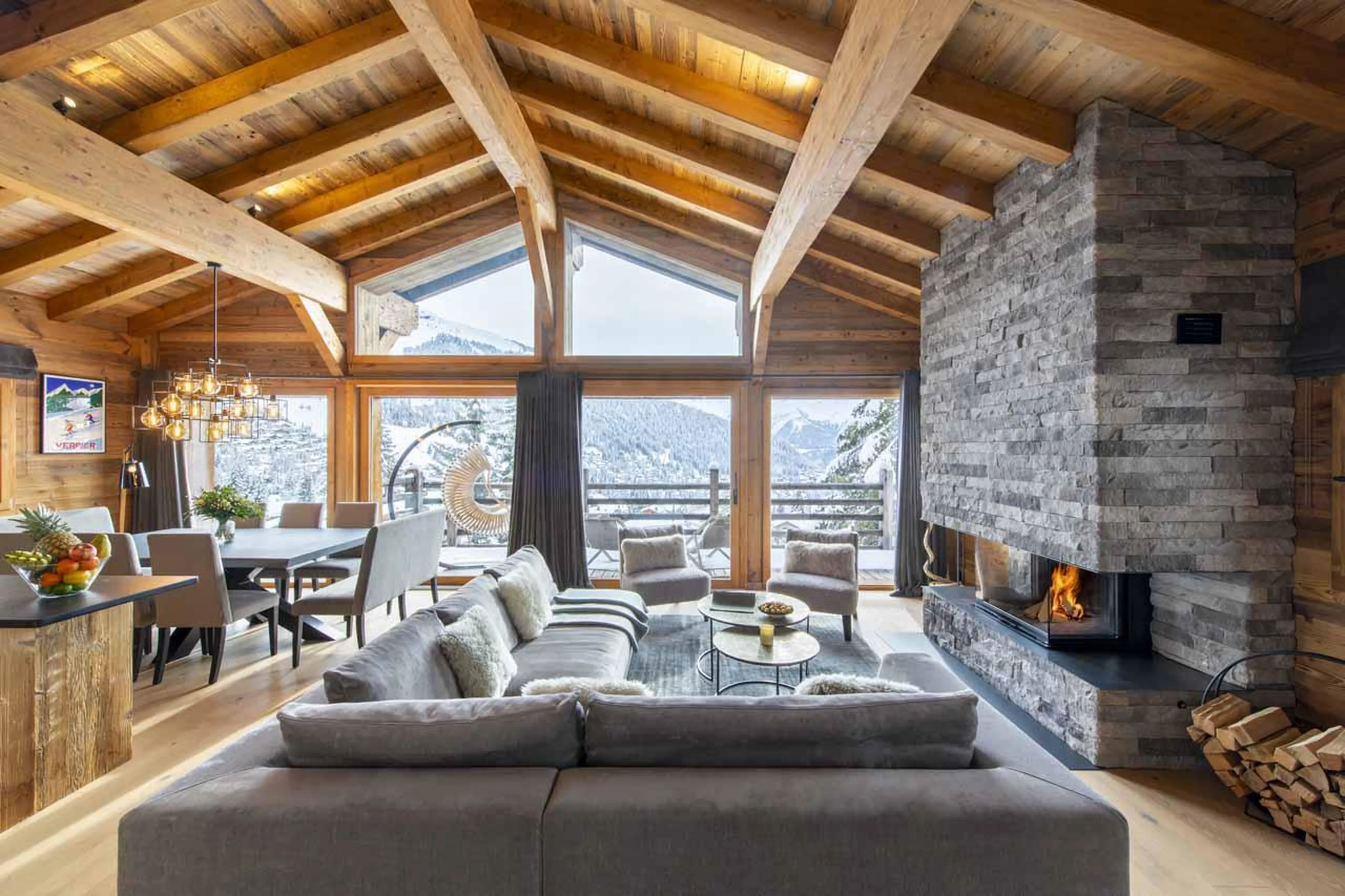 Open-plan living room with sofa, dining, and kitchen area at Chalet Cortil in Verbier