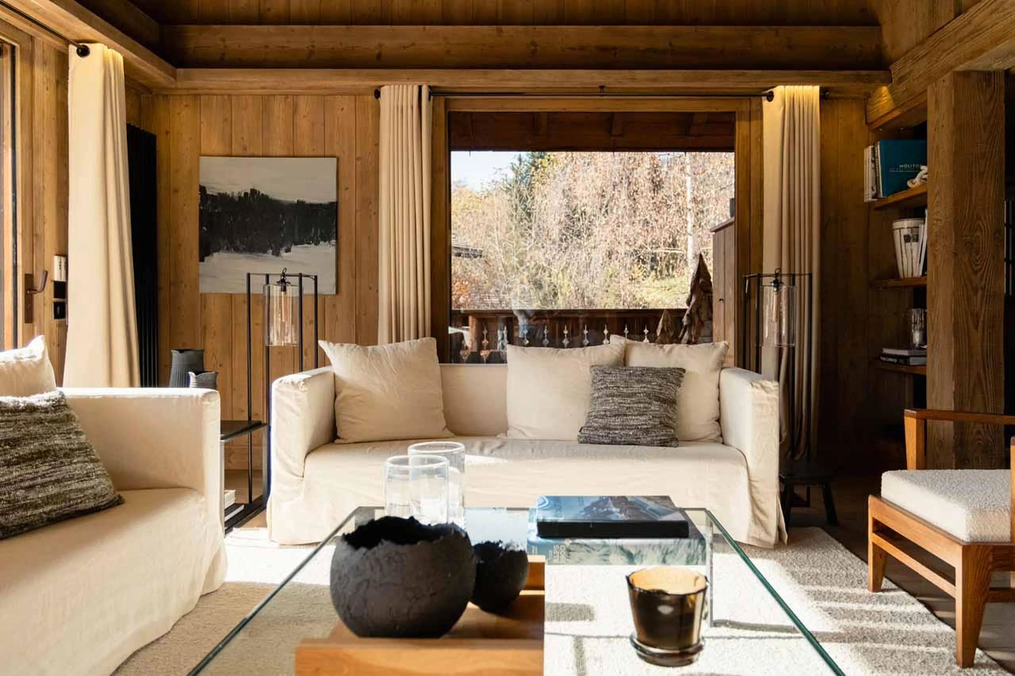 Sofas and coffee table in front of floor-to-ceiling windows in Chalet Donatien, Megeve
