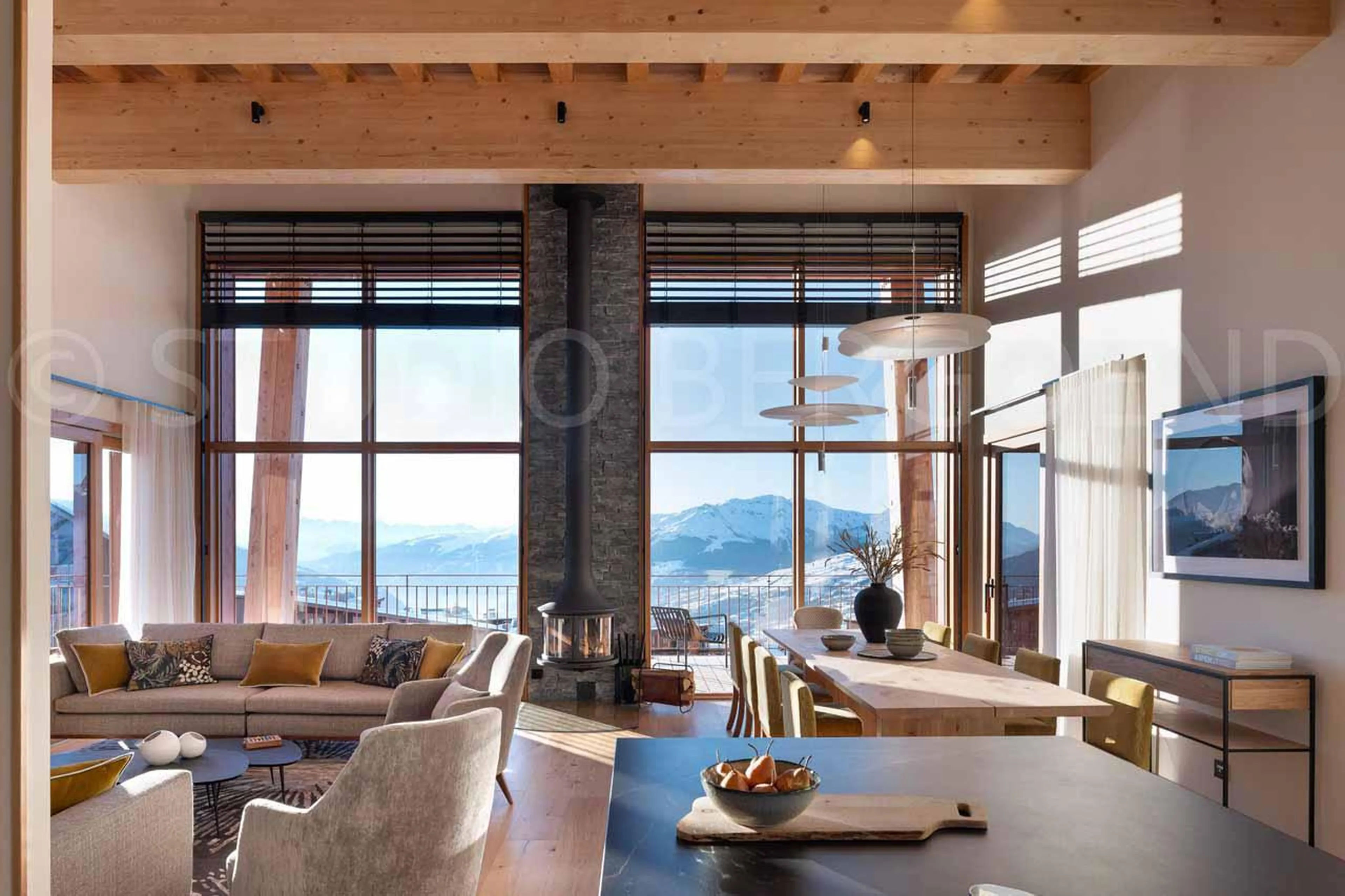 Open-plan living space with cosy sofa area, dining table and fireplace at Eden Mille 8 in Les Arcs