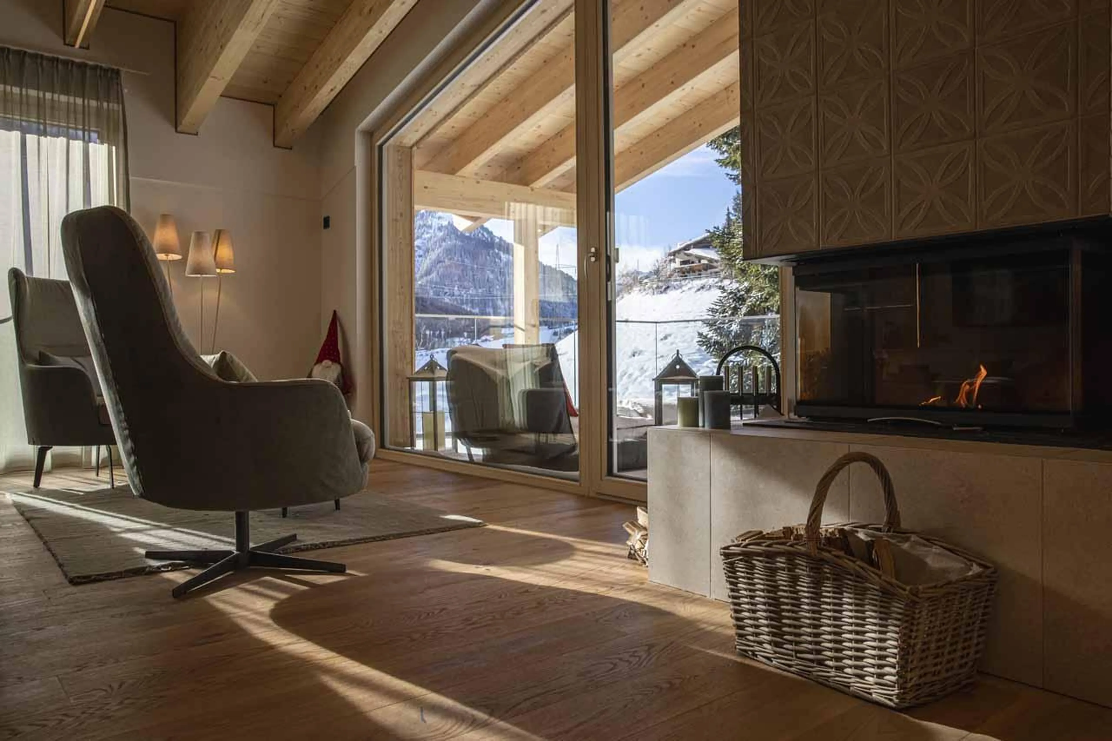 Fireplace and armchairs set beneath glass doors at Chalet Frieda in St Anton