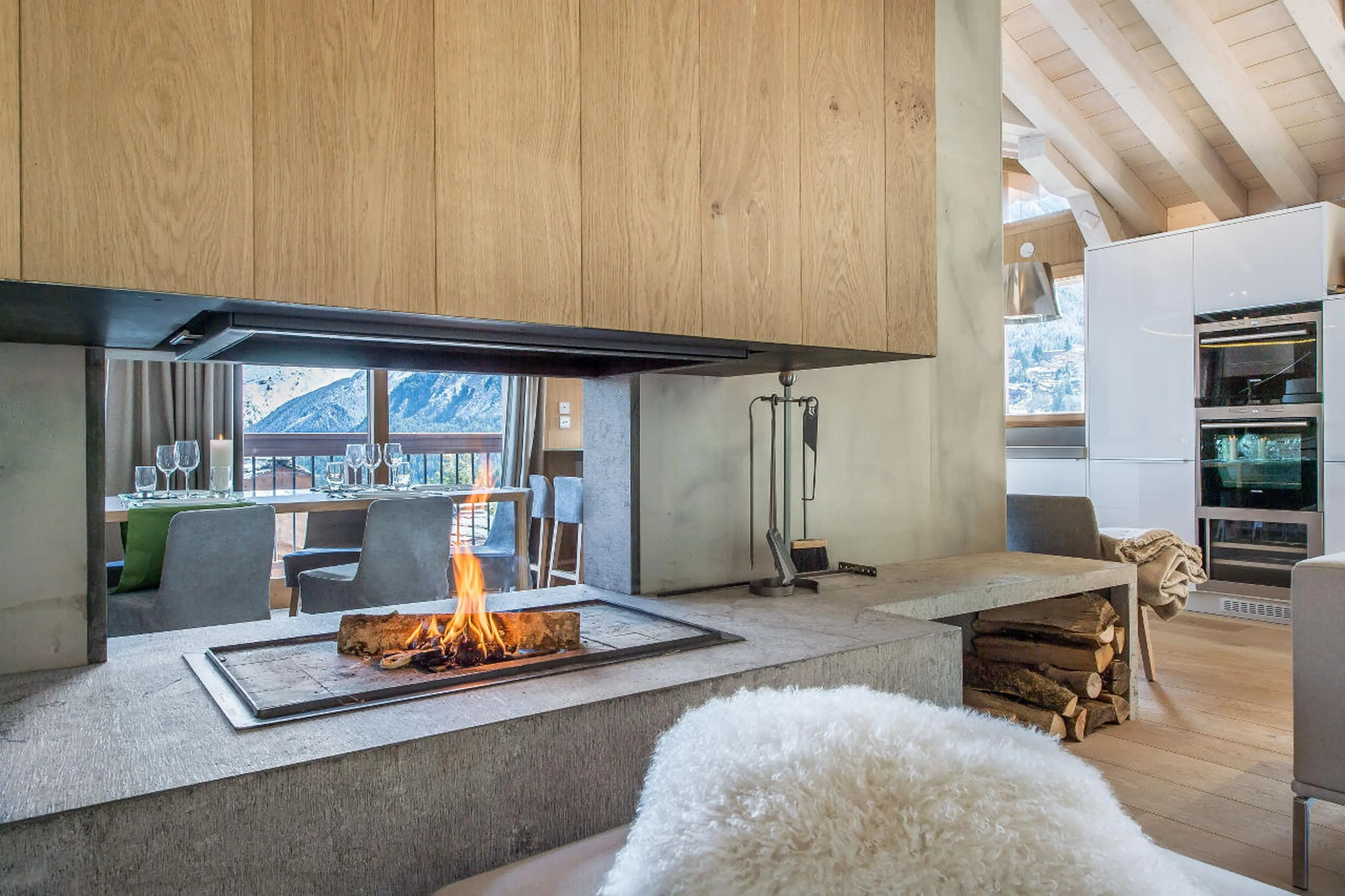 Open fireplace divides open plan kitchen and living area in Chalet Kibo in Courchevel 1550