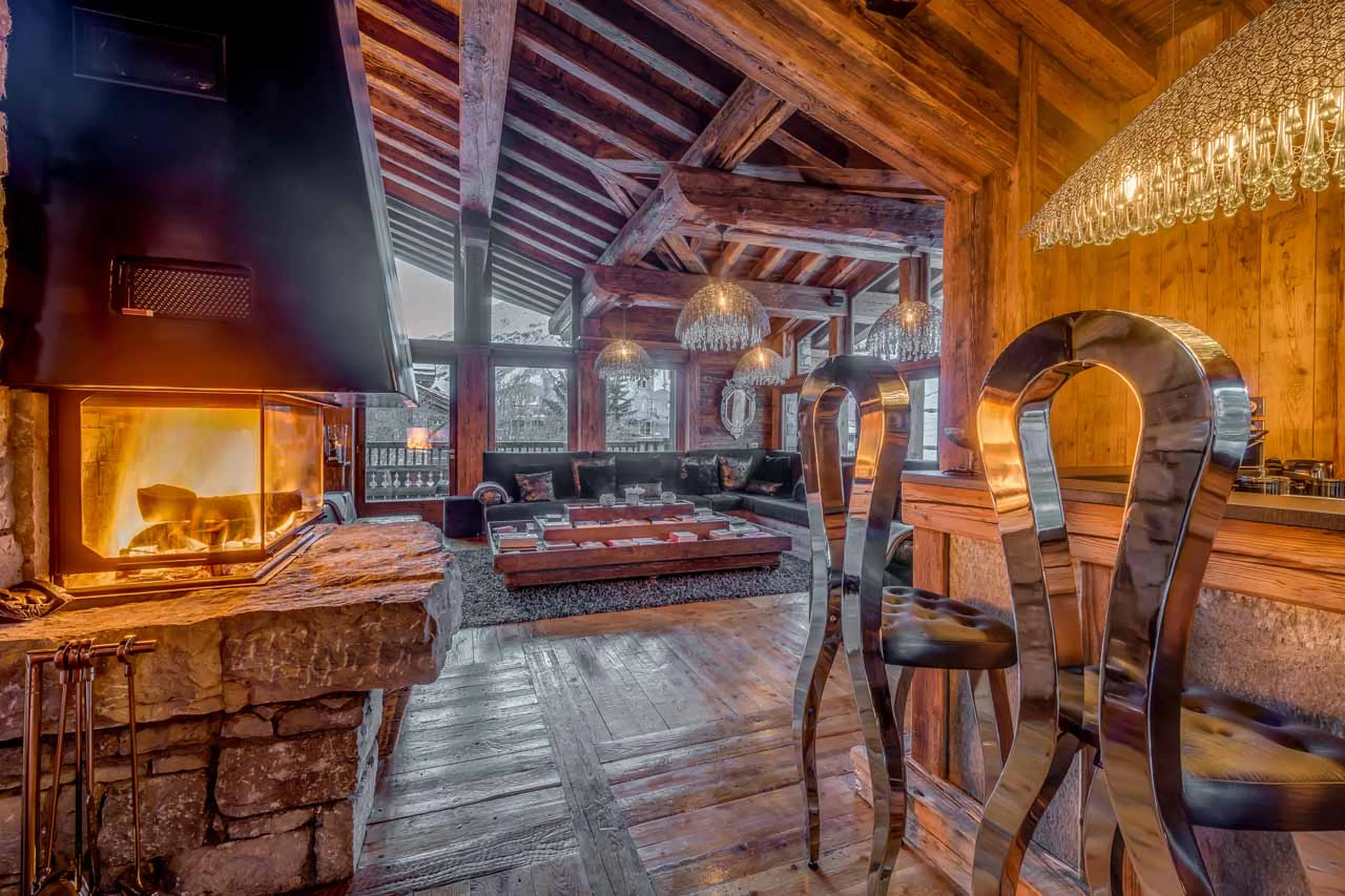 Open plan living and dining area revolves around a central fire place in Chalet Marco Polo in Val d’