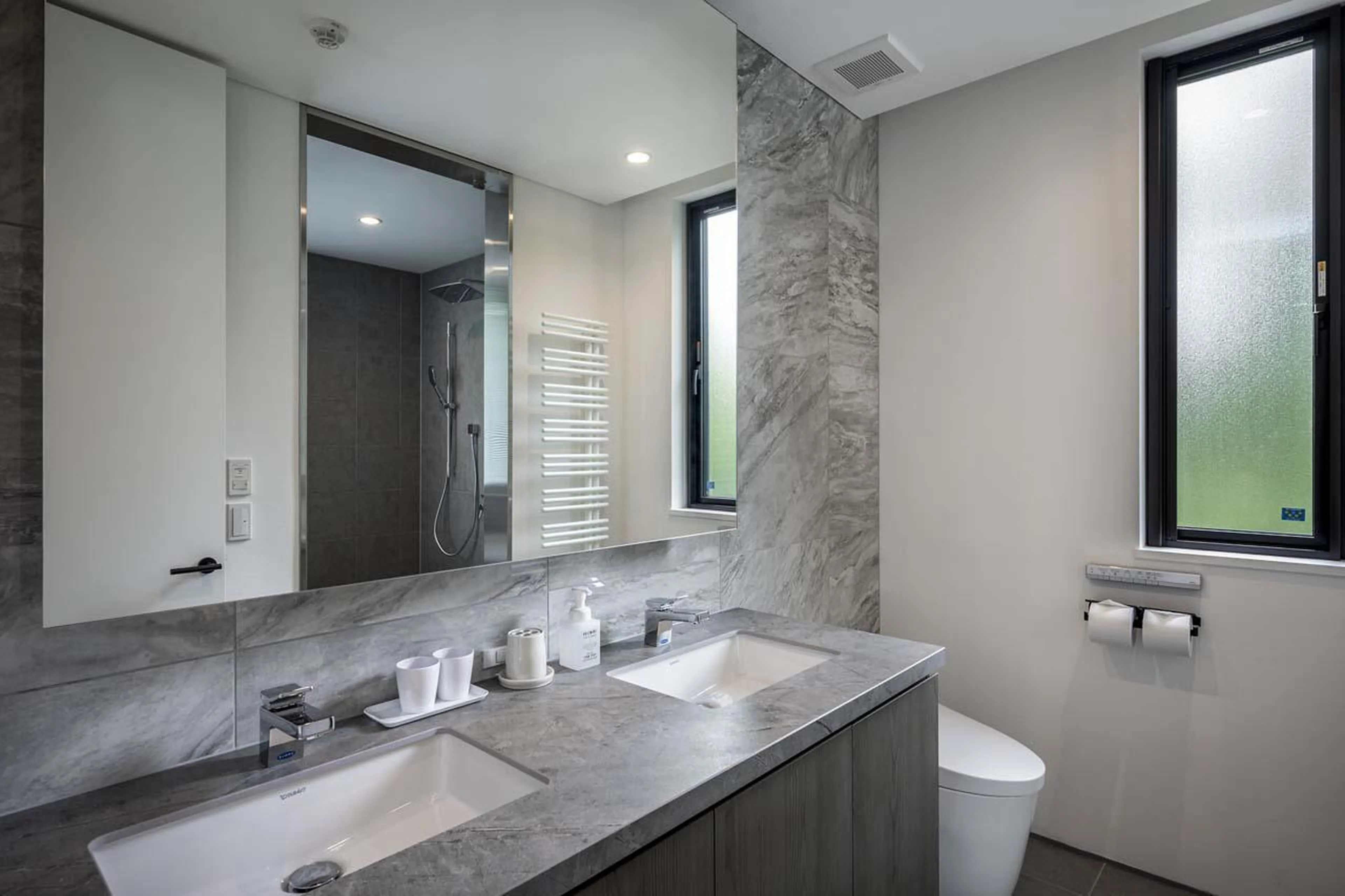 En-suite bathroom with double basin, bath and shower at Chalet Ryoun in Niseko