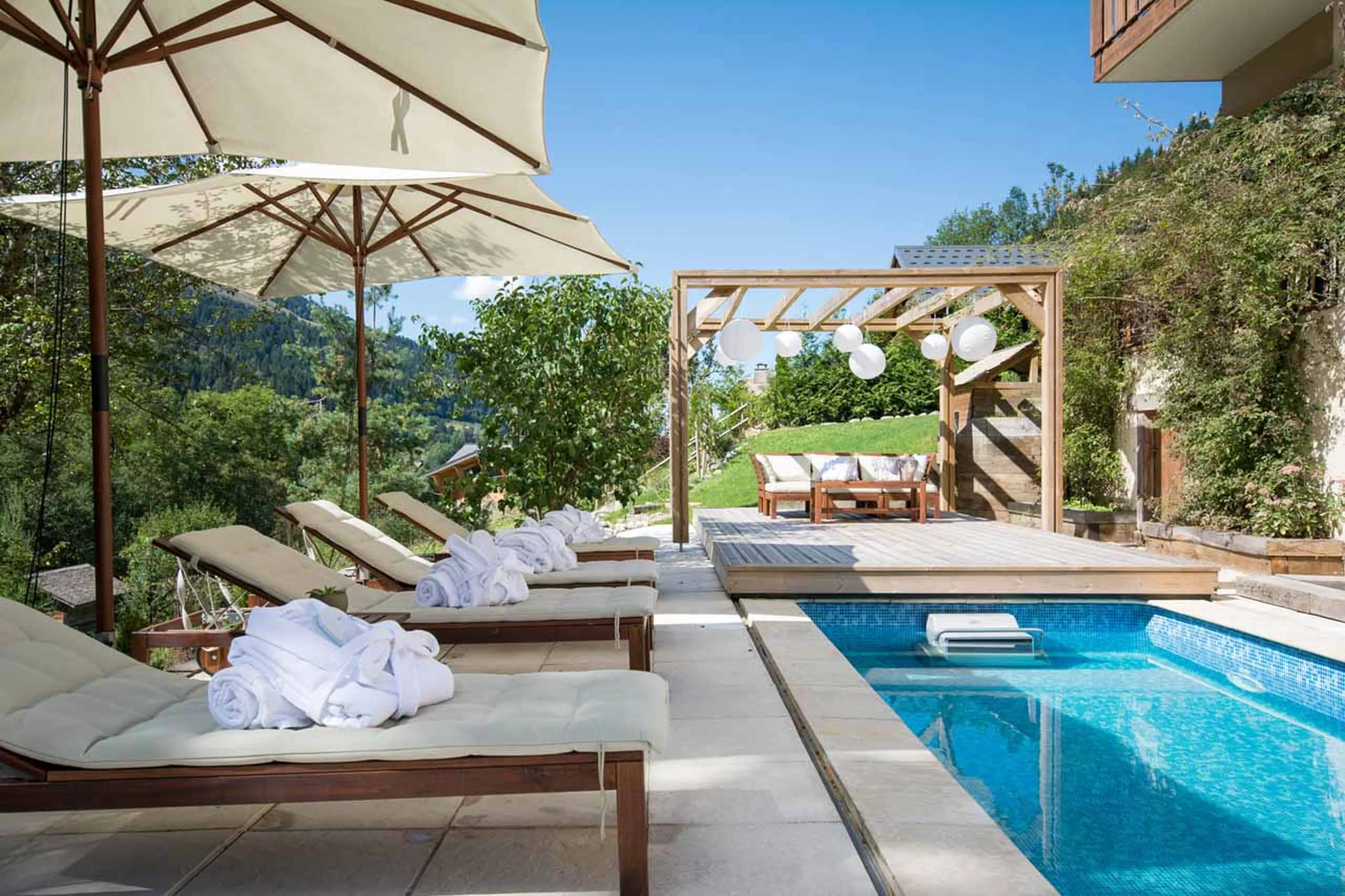Sun loungers beside pool at Chalet Twenty 26 in Morzine