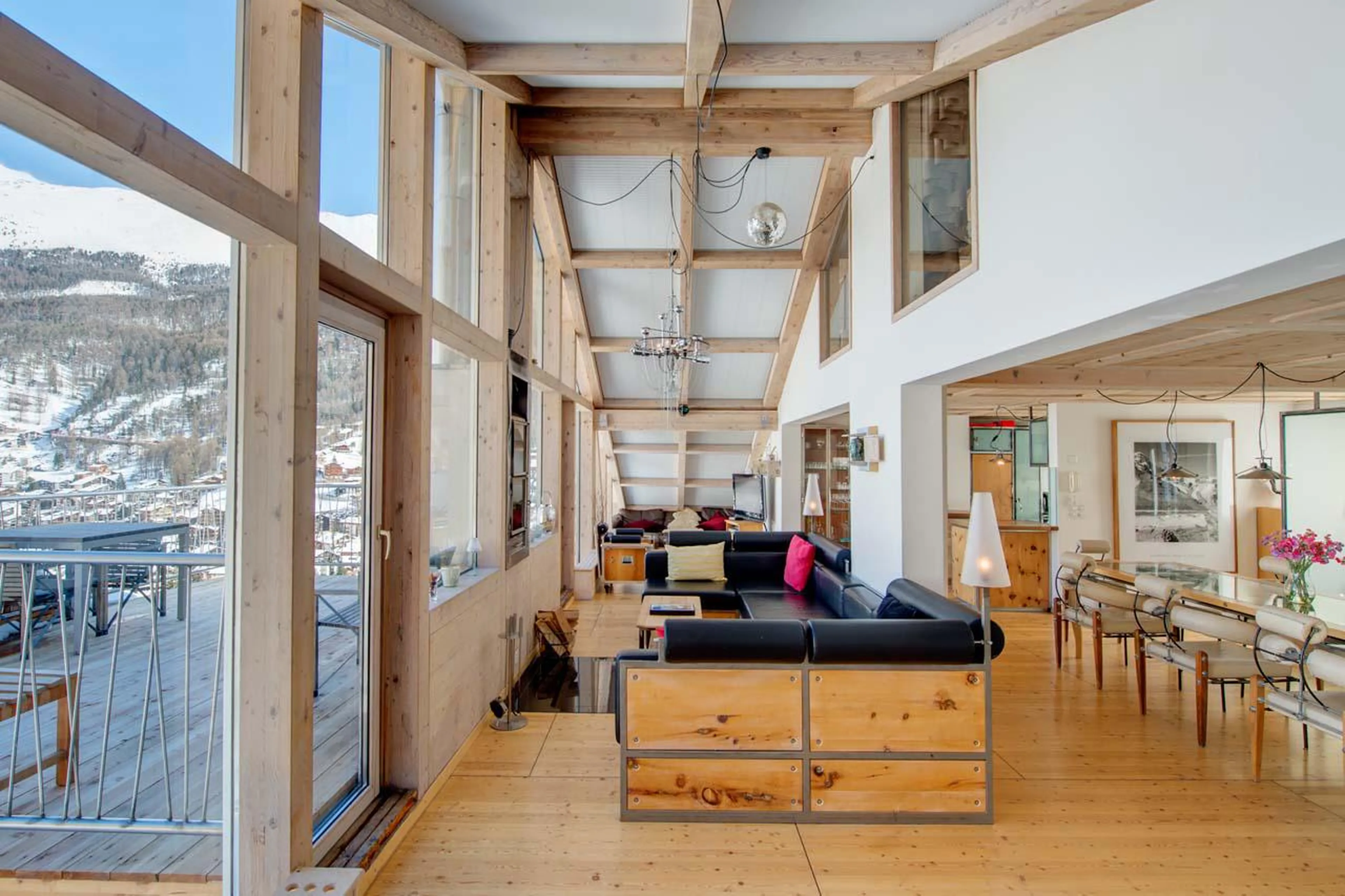 Open-plan living area with dining table, sofas, TV and fireplace at Heinz Julen Penthouse in Zermatt