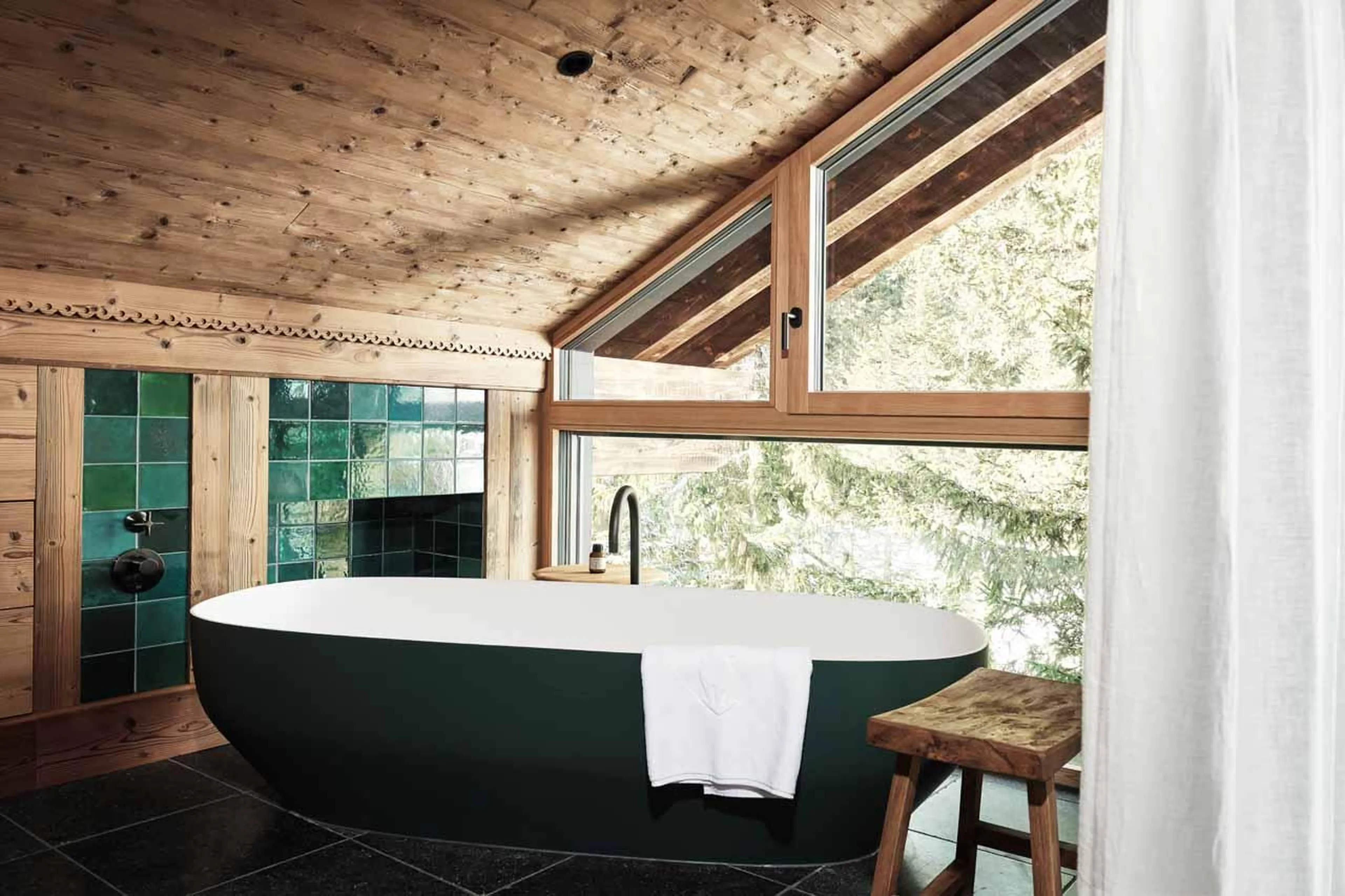 Freestanding bathtub in bedroom in front of vaulted window in Lech Lodge Loft, Lech