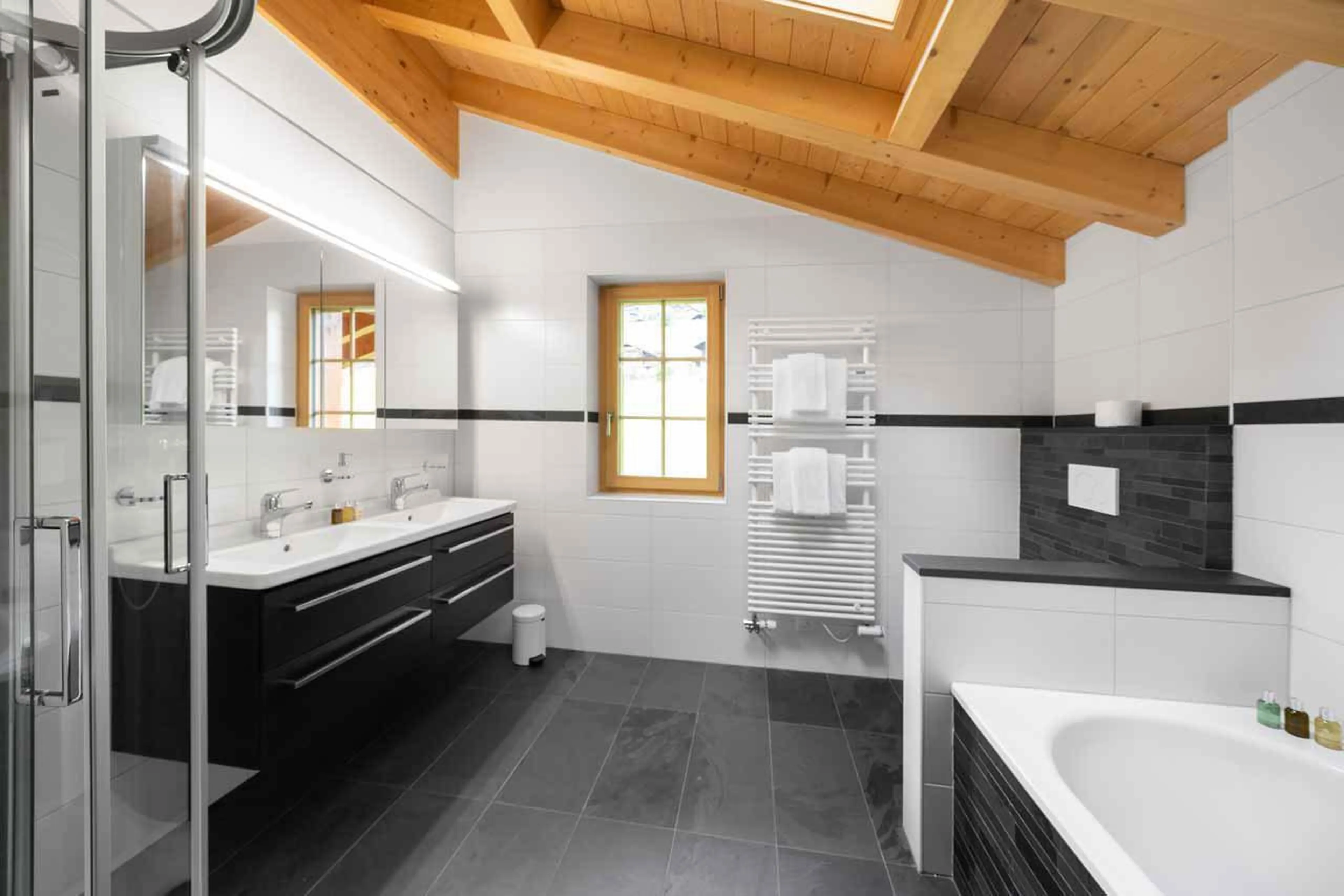 En-suite bathroom with shower, bath and his and hers sinks at Chalet Alia in Grindelwald