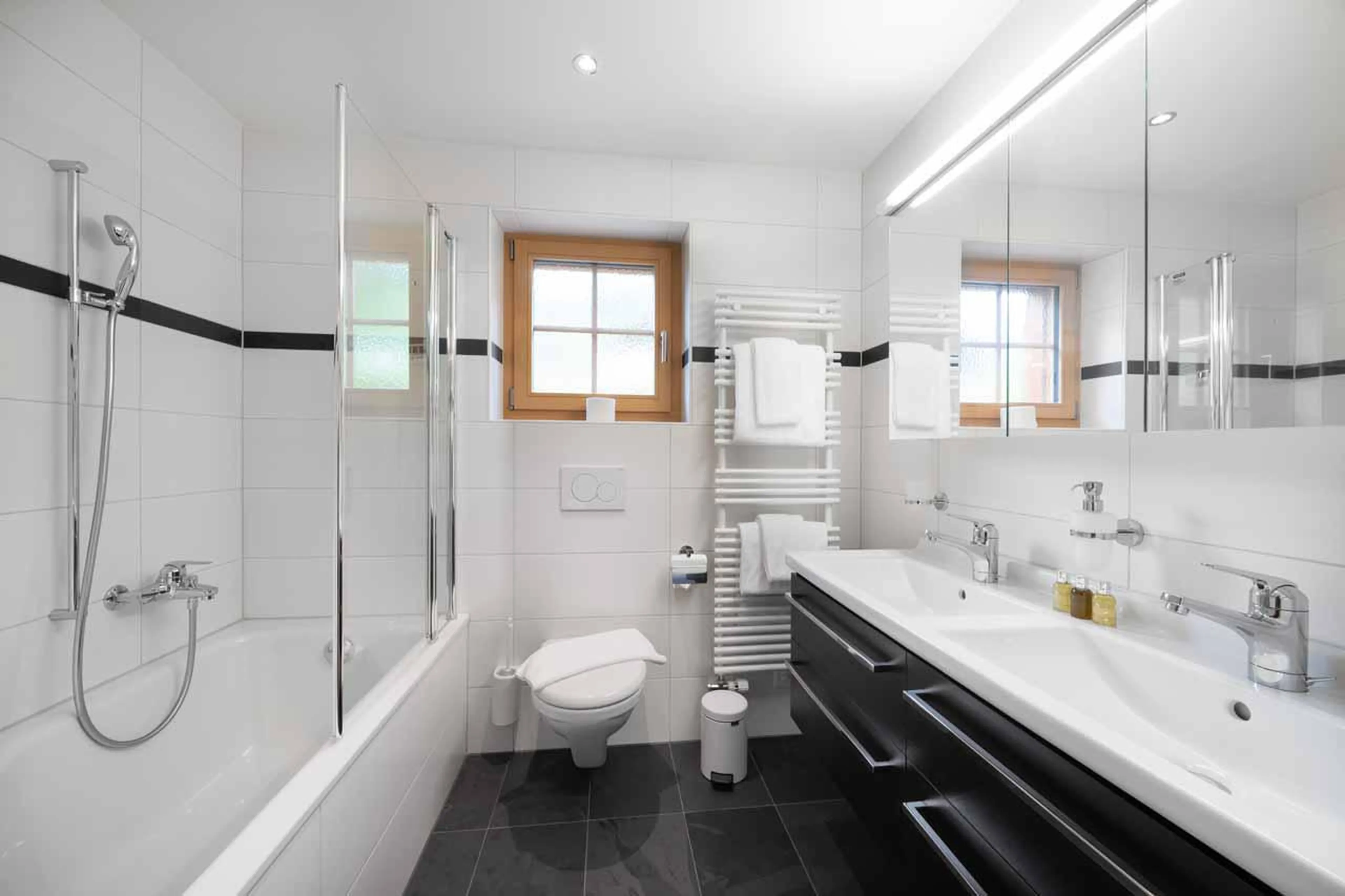 En-suite bathroom with bath and his and hers sinks at Chalet Alia in Grindelwald
