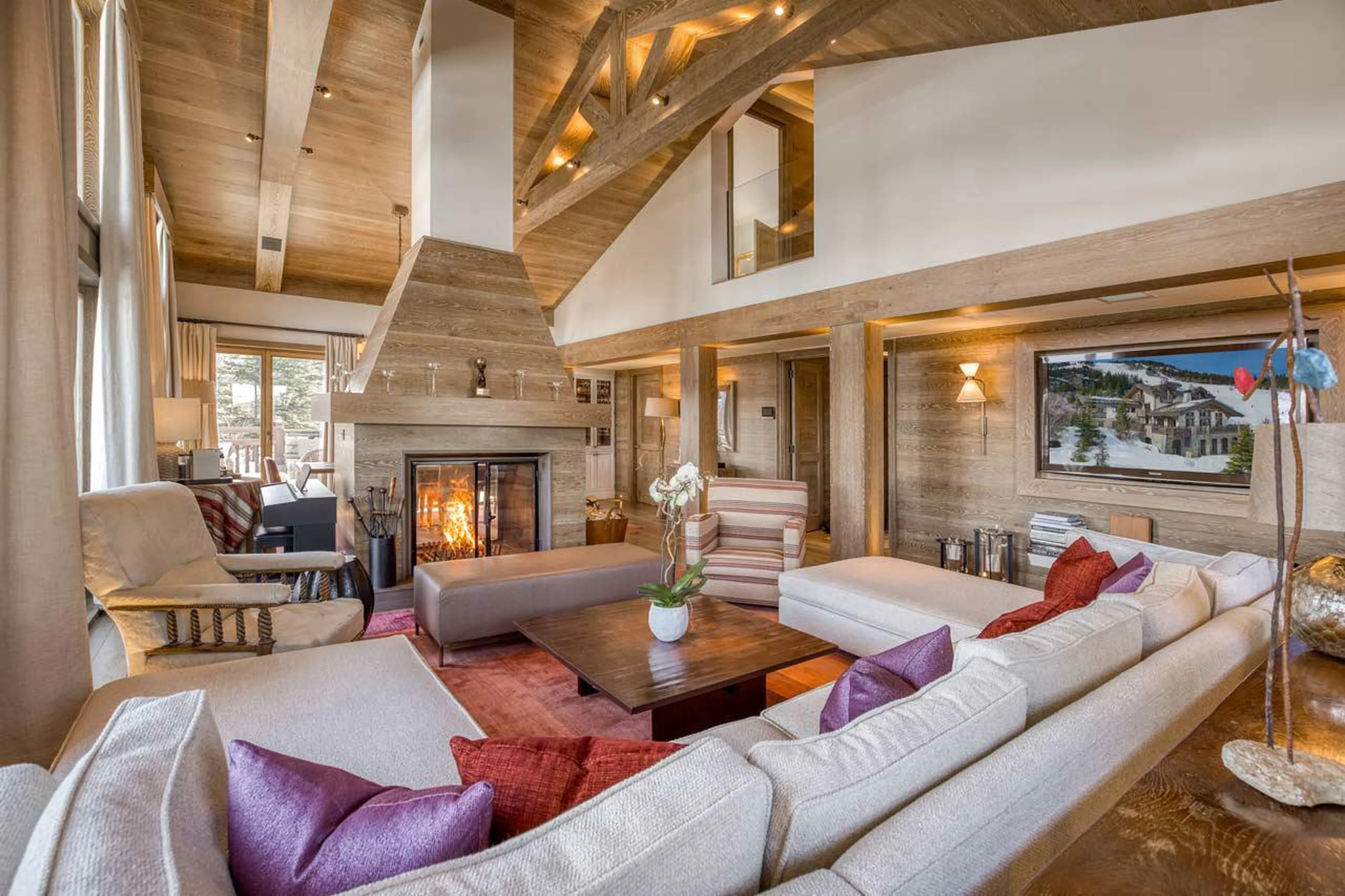 Living area with vaulted ceiling and cosy fireplace in Shemshak Lodge in Courchevel 1850